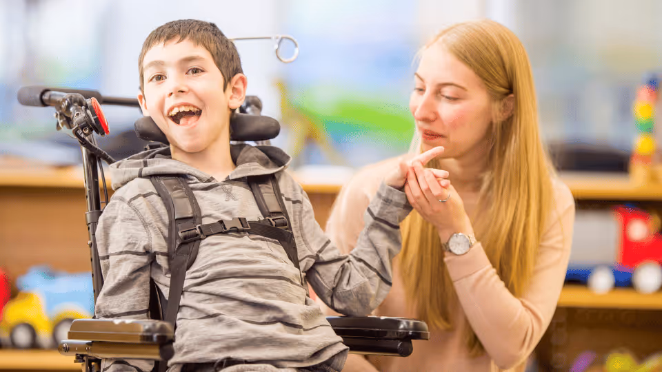A woman and a boy in wheelchairs engage in a physical therapy session, guided by a professional therapist.