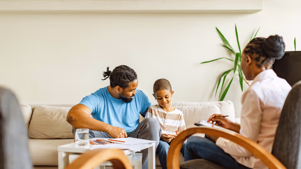 A family engaged in a child therapy session, sitting together on a couch, fostering a supportive environment.