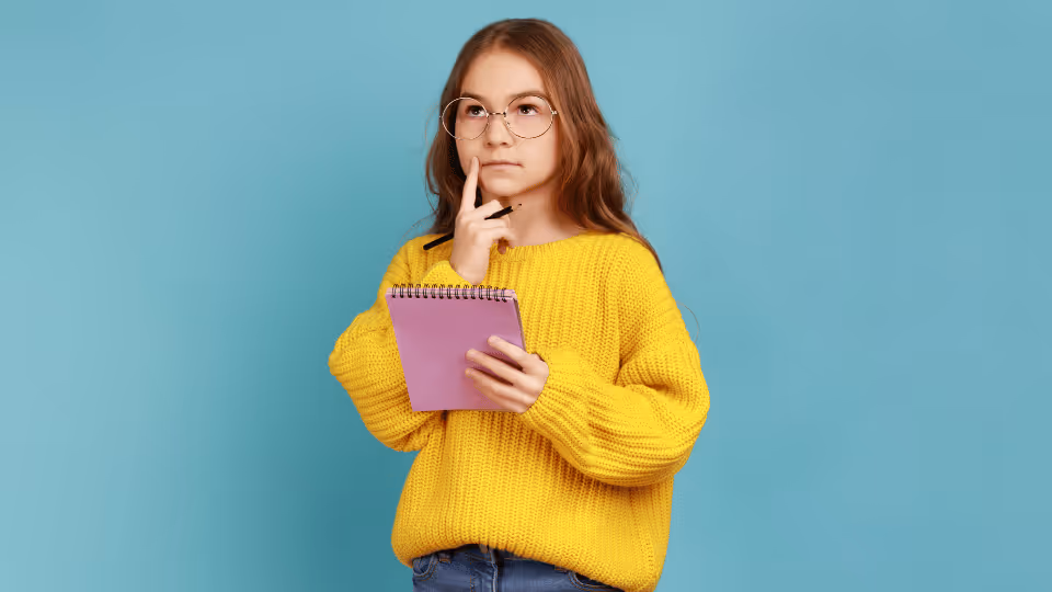 A young girl in a yellow sweater holds a notebook, contemplating her choice of a physical therapist.