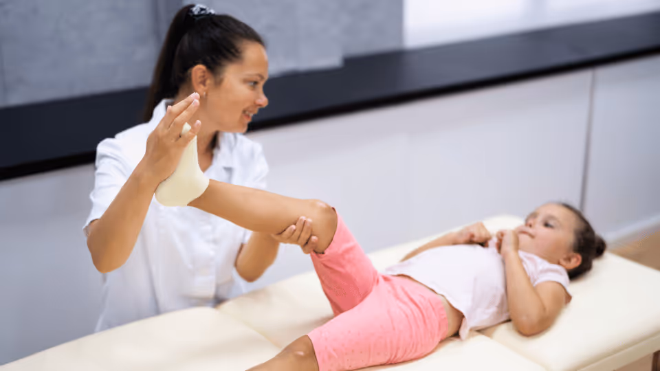 A woman assists a young girl during a physical therapy session, focusing on rehabilitation and support.