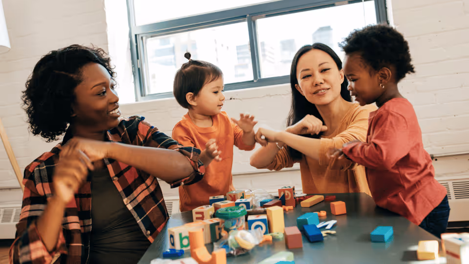 A woman and two children joyfully playing with blocks, fostering creativity and promoting a healthy lifestyle through play.