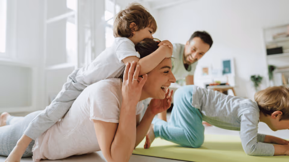 A family practicing yoga together at home, promoting wellness and physical therapy for children in a supportive environment.