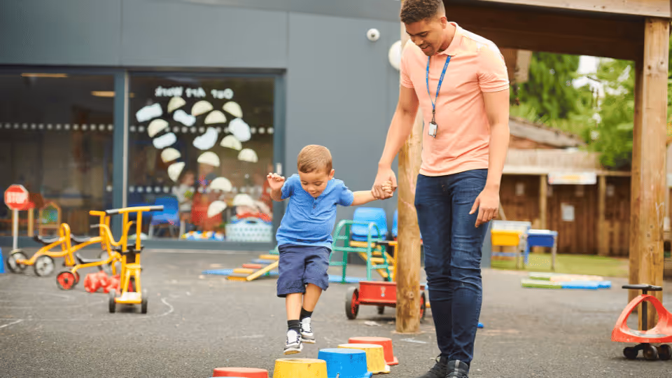 A man and a child stand together on a playground, engaging in activities to support physical therapy goals.