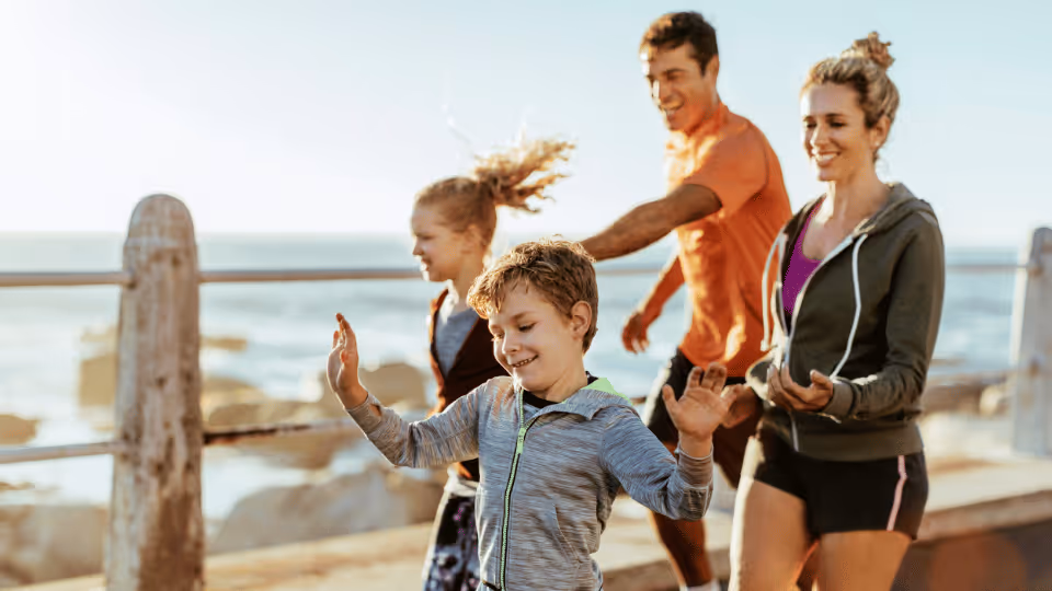 A family joyfully running on a beach, symbolizing the pursuit of physical therapy goals through active engagement.