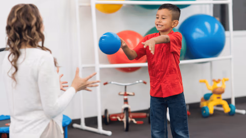 A boy joyfully plays with a ball in a gym, highlighting the importance of engaging patients in goal-setting activities.