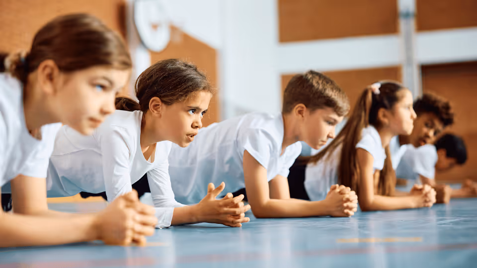 Children performing push-ups on a gym floor, engaging in physical therapy to enhance strength and coordination.