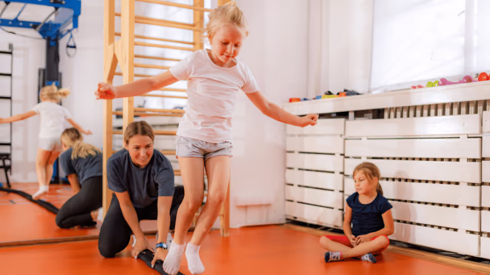 A young girl leaps into the air, demonstrating agility and coordination during a physical therapy session.