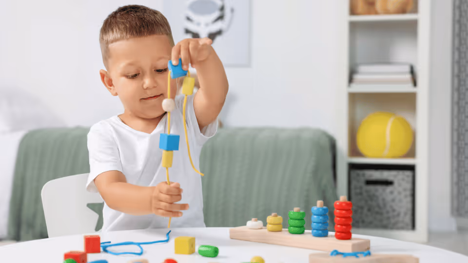 A young boy engaged in play with wooden toys, enhancing his fine motor skills through interactive learning.