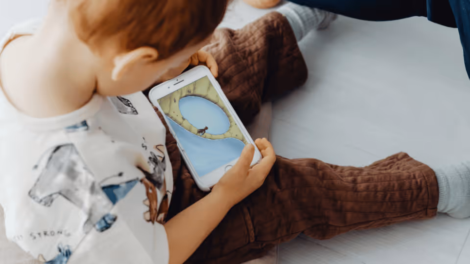A child engaged with a mobile phone, highlighting the role of technology in early intervention strategies.