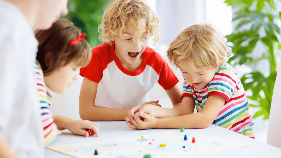 Three children engaged in a board game, participating in occupational therapy to enhance their skills and social interaction.