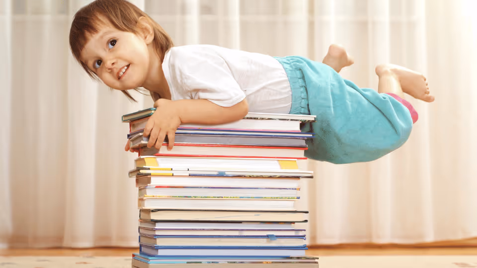 A young girl rests on a stack of books, engaging with educational materials on letter sounds and rhymes.