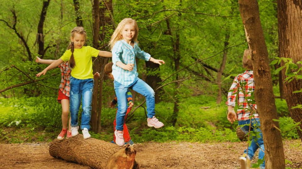 Children joyfully playing on a log in a lush forest, showcasing their creativity and connection with nature.
