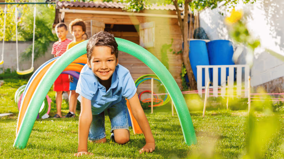 A boy joyfully engages with a vibrant play structure, showcasing active play with colorful obstacle course elements.