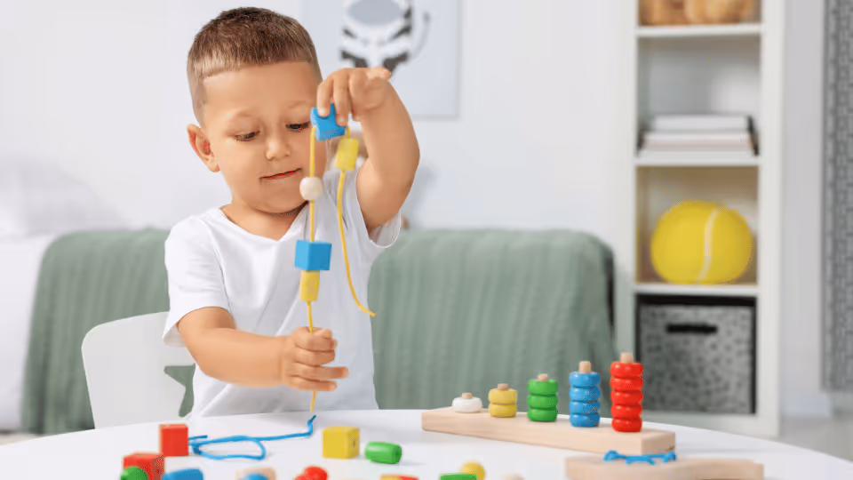 A young boy joyfully playing with colorful wooden toys, enhancing his fine motor skills at the age of two.