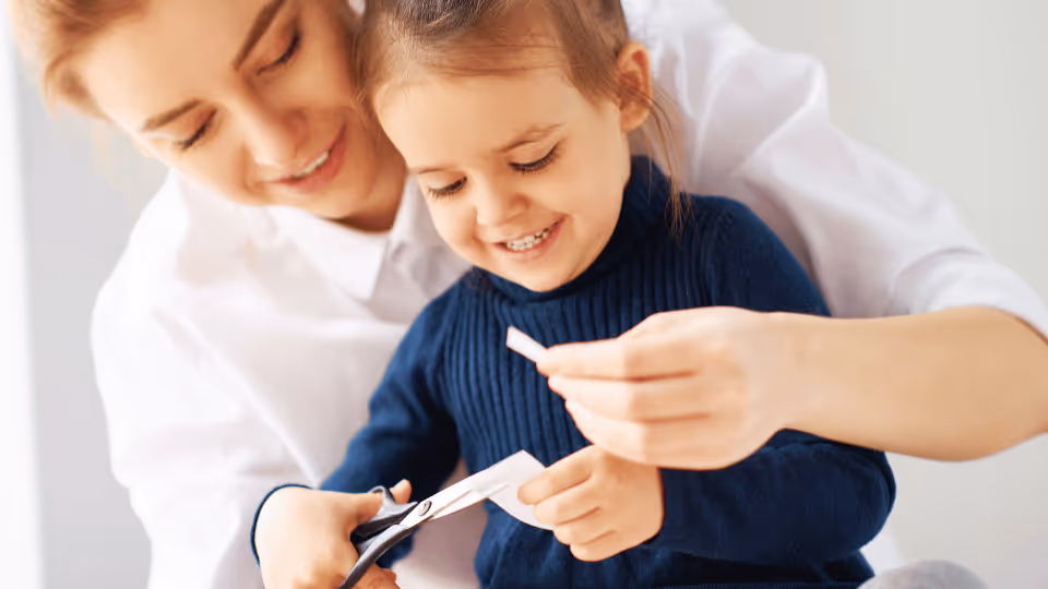  A woman and a child sit together on a couch, engaging in activities that promote fine motor skills development.