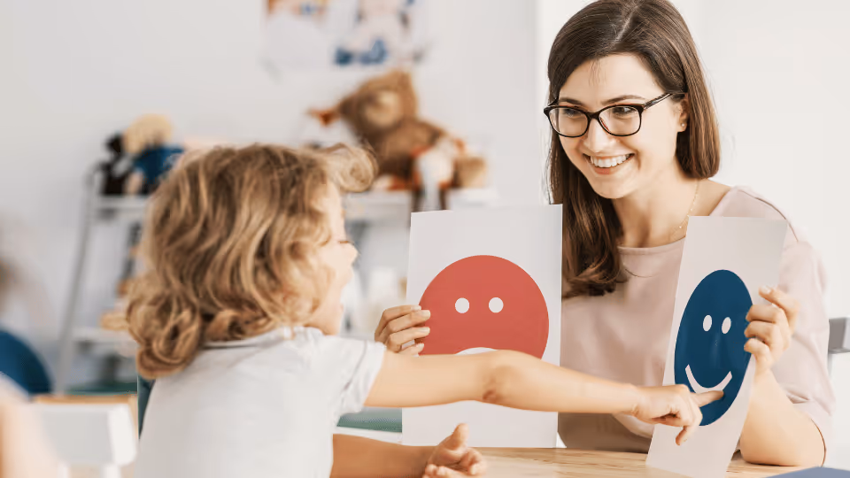 A woman and child joyfully hold up smiley face signs, symbolizing positive outcomes in speech therapy after evaluation