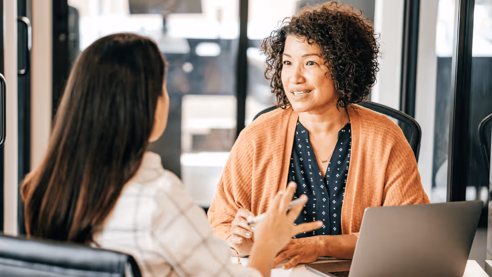 A woman engages in conversation with another woman in an office setting, discussing the Coral Care Providers vetting process