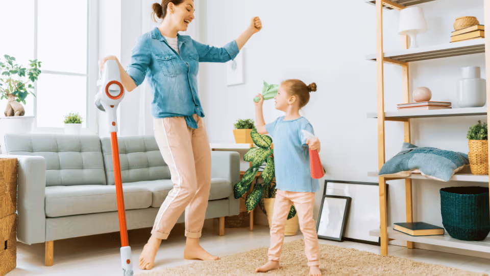 A woman and child joyfully engage with a vacuum cleaner, symbolizing preparation for home evaluation and child readiness