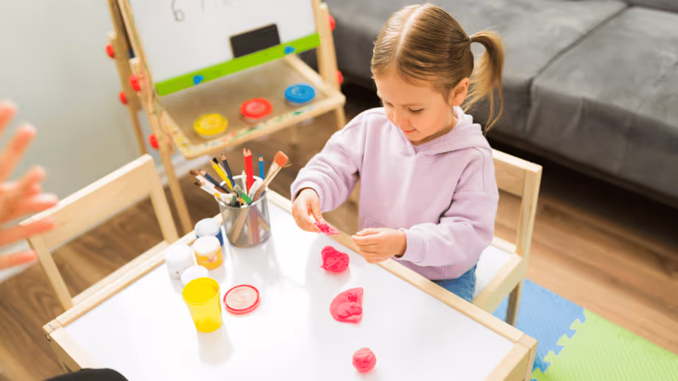 A child joyfully engages with a toy at a table, symbolizing the start of their therapeutic journey
