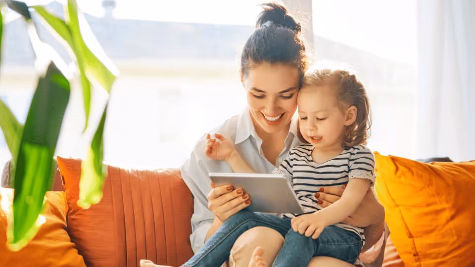 A woman and child seated on a couch, engaging with a tablet, symbolizing family connection and informed decision-making.