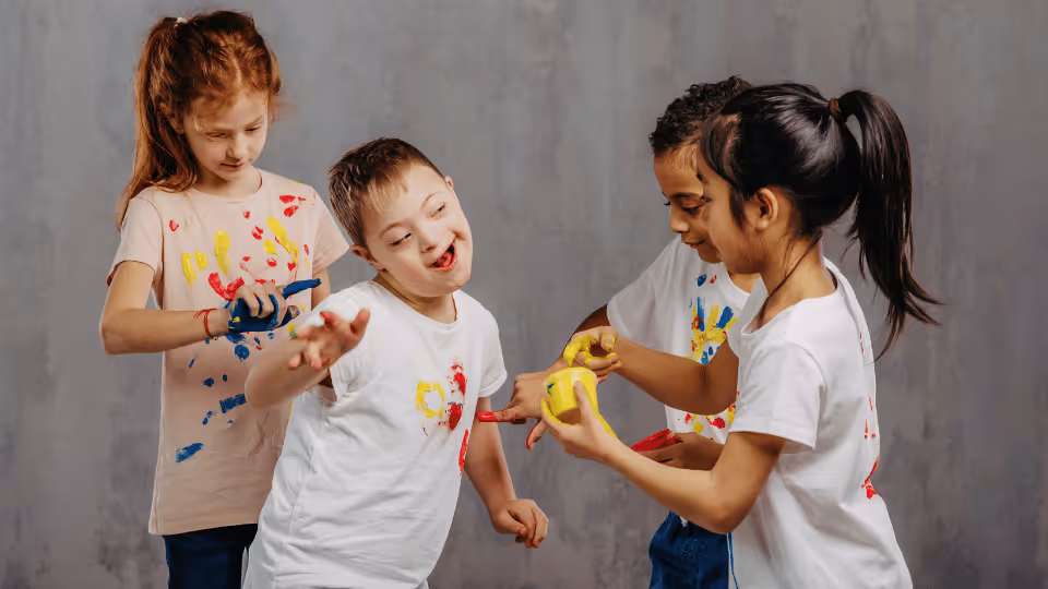 Children joyfully painting with brushes, engaging in creative play at a Houston resource center for kids.