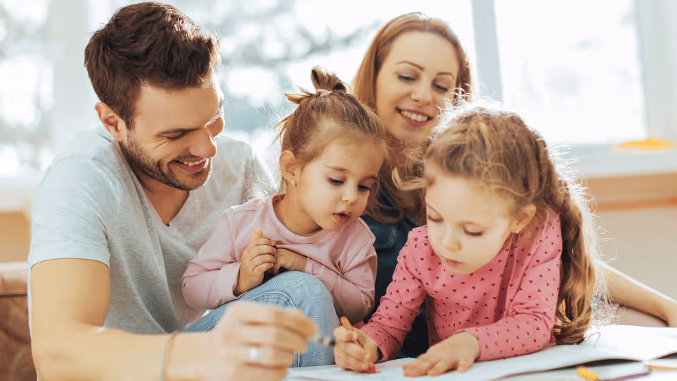 A family gathers on a couch, engaged in drawing, reflecting the importance of creativity in parent support groups in Boston.