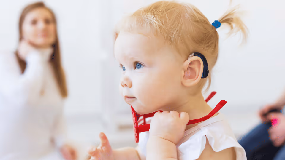 A baby with a red headband in the foreground, with a woman visible in the background, representing Houston's developmental disability councils.