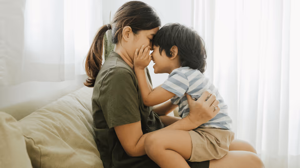 A woman and child sitting on a couch, engaged in early intervention and pediatric speech therapy activities