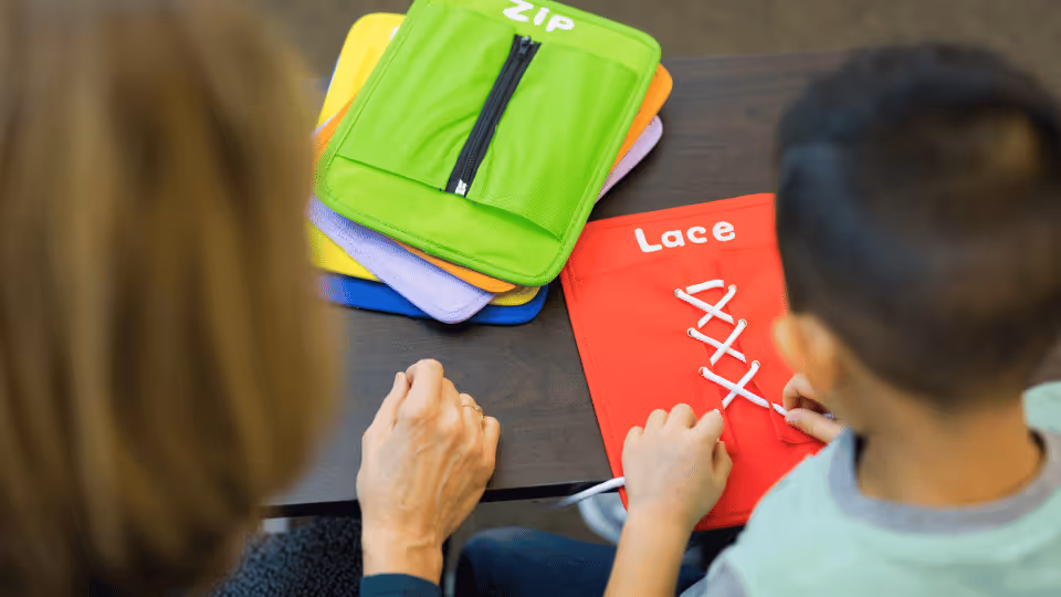A woman and a child sit at a table with a bag of colorful items, highlighting pediatric occupational therapy in Austin, Texas