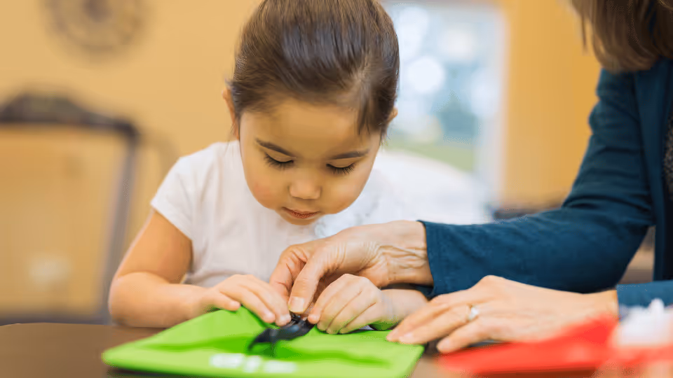 A woman assists a young girl with zippers, highlighting pediatric occupational therapy in Houston, Texas.