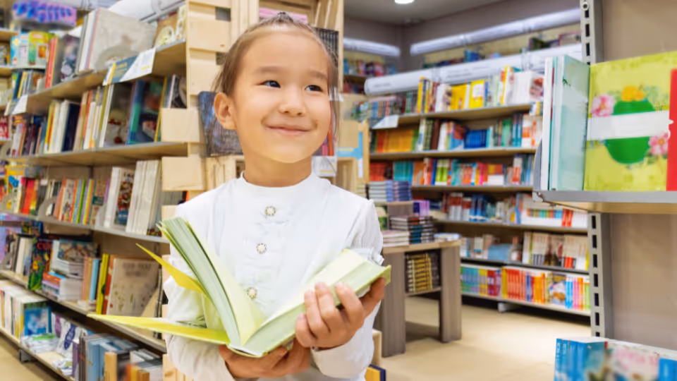 A young girl holds a book while exploring a public library in Boston