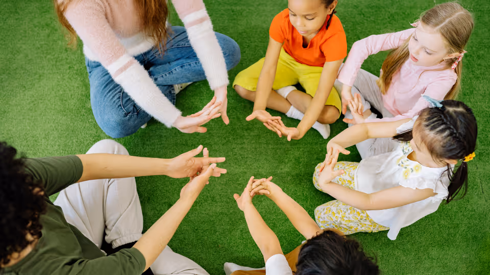 Children and adults sit in a circle, engaging in a hands-on activity, representing developmental disability councils in Austin