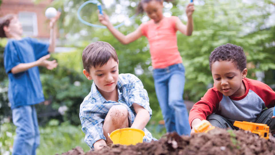 Children joyfully playing in the dirt, engaging in outdoor activities essential for physical therapy and development.