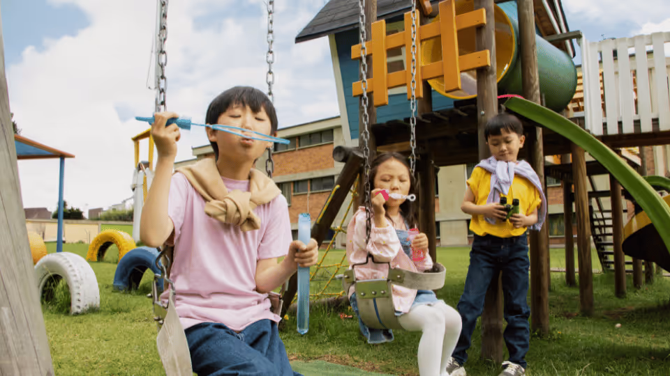 Children enjoying swings in a playground, participating in articulation and phonological games in the yard.