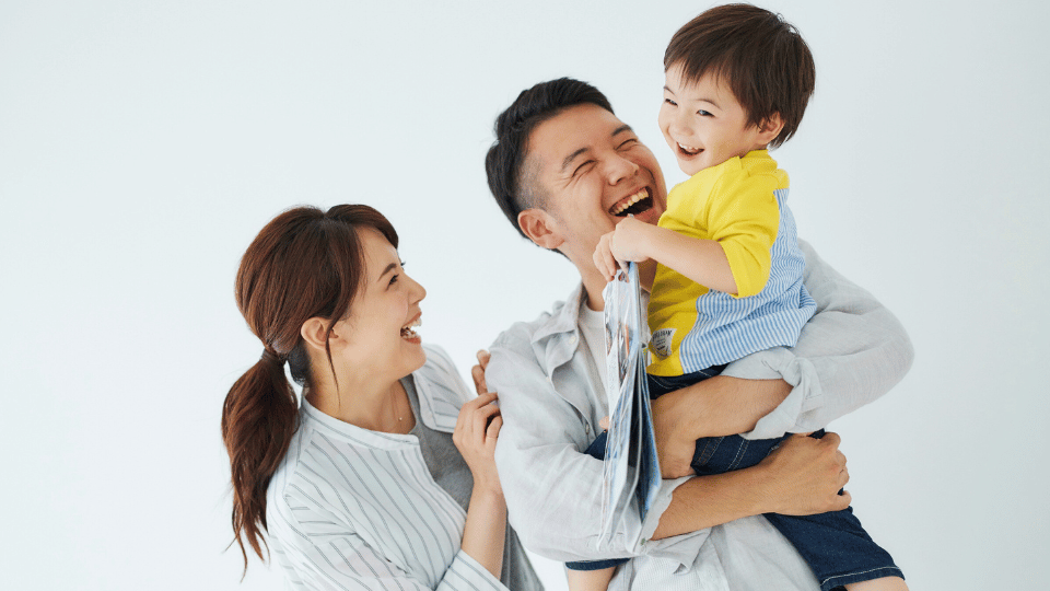 A man and woman smile while holding a child, representing family support resources for parents in Austin, TX