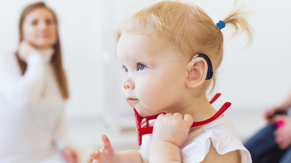 A baby with a red headband in the foreground, with a woman visible in the background, representing Houston's developmental disability councils.