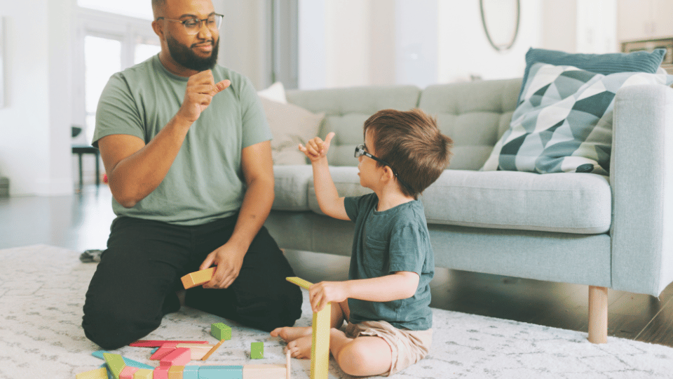 A father and son joyfully playing with colorful blocks, promoting creativity and bonding, supported by Boston's developmental disability councils.