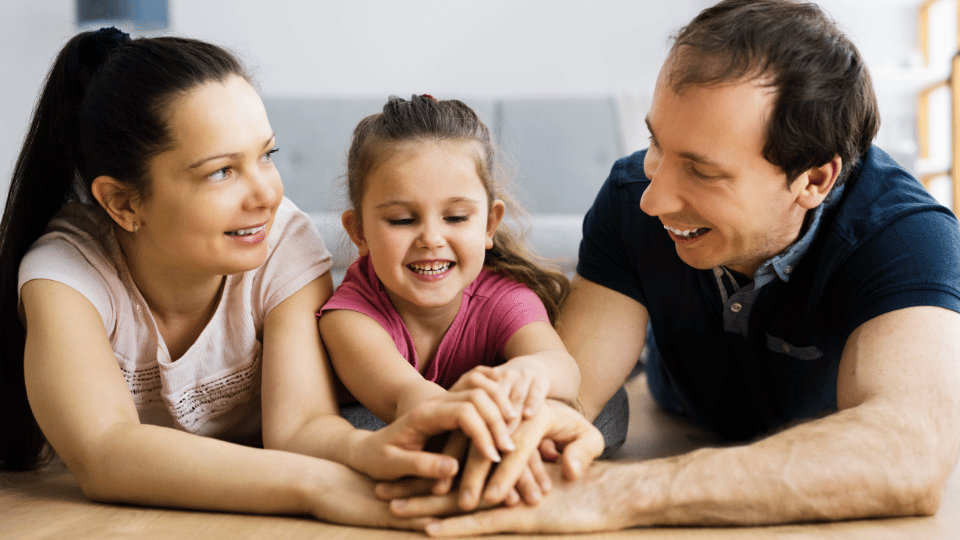 A joyful family lies on the floor, showcasing togetherness, linked to resources for parents in Boston, MA