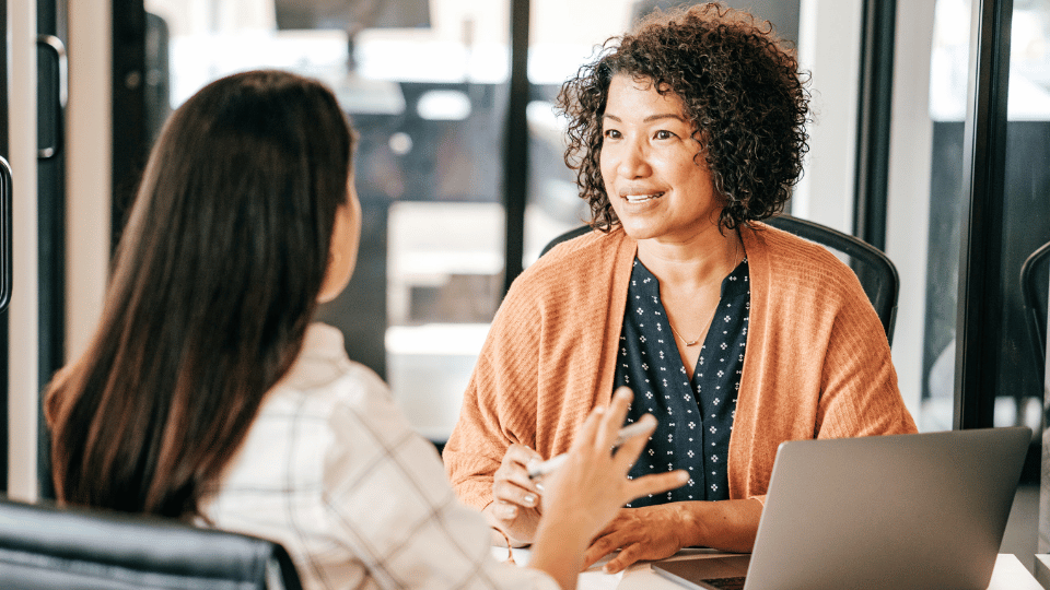 A woman engages in conversation with another woman in an office setting, discussing the Coral Care Providers vetting process