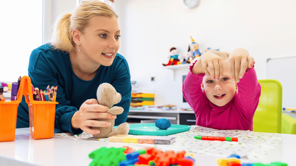 A woman and child engage with toys in a classroom, highlighting fun gifts for kids in occupational therapy.