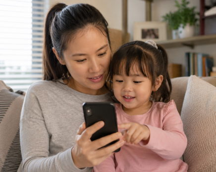 Parent and young child looking at a phone together at home while searching for local activities