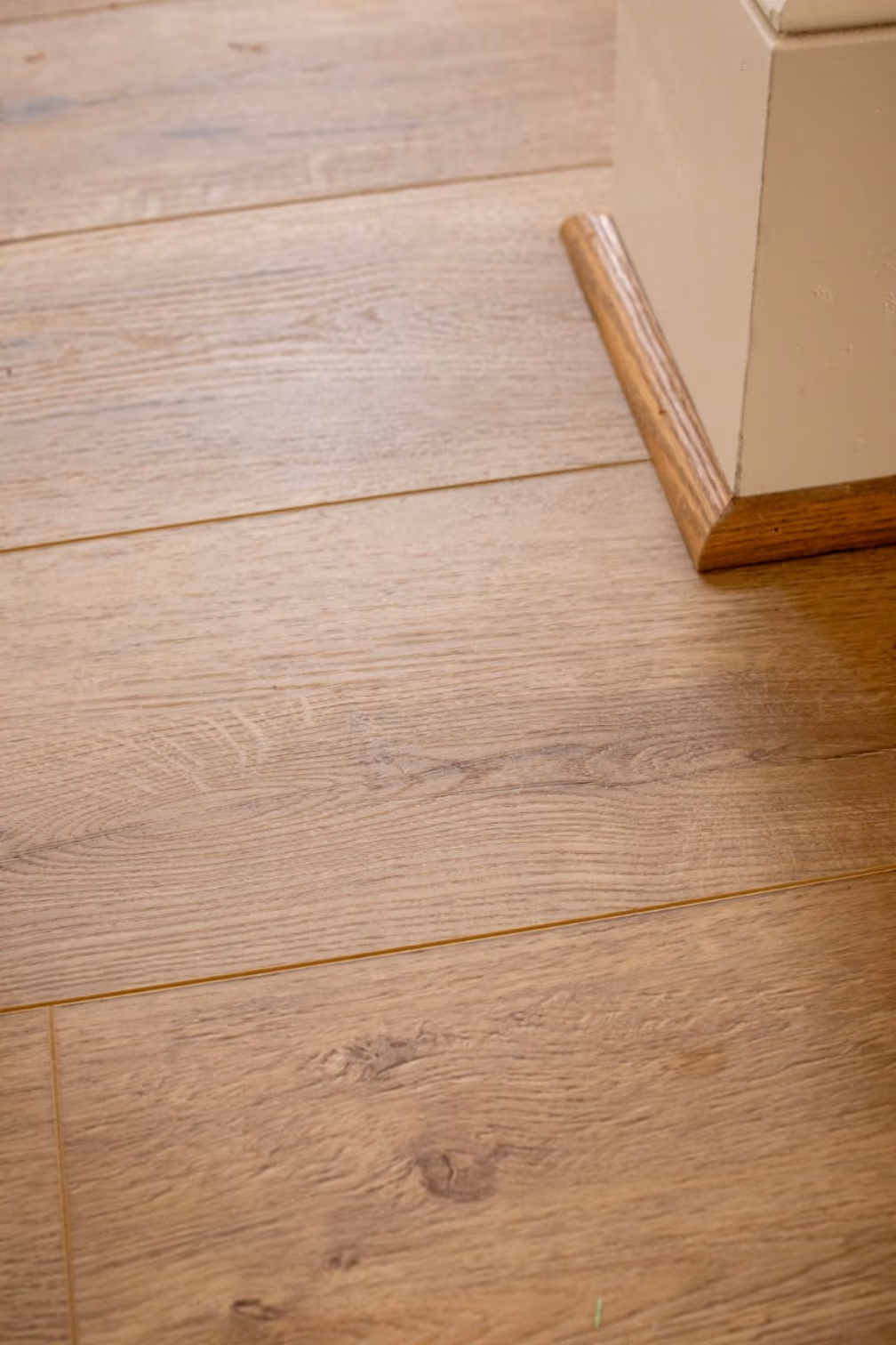 close-up of brown wood-looking luxury vinyl flooring and quarter round