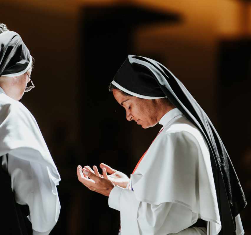 A priest processing through a city street with Jesus in a monstrance.