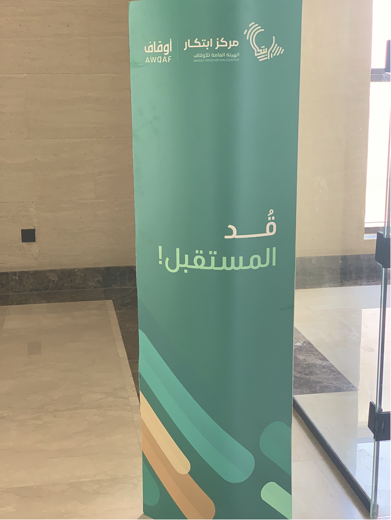 Green banner with Arabic text, Awqaf Innovation Center logo, and abstract colored shapes at the bottom.