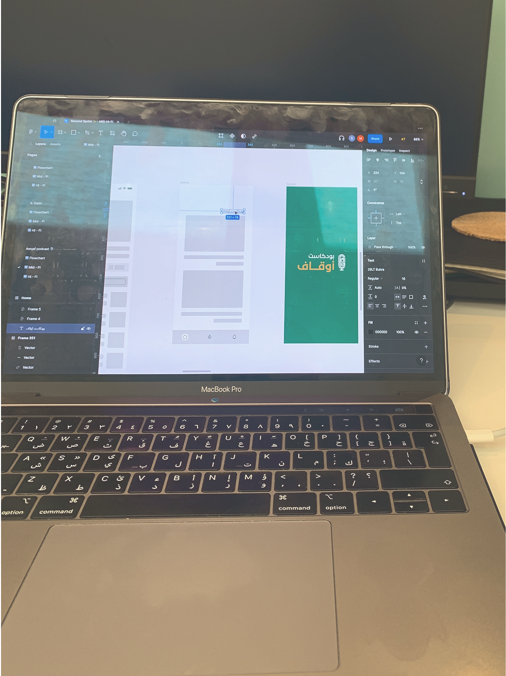 MacBook Pro showing a Figma design interface with Arabic text and UI wireframes on screen.