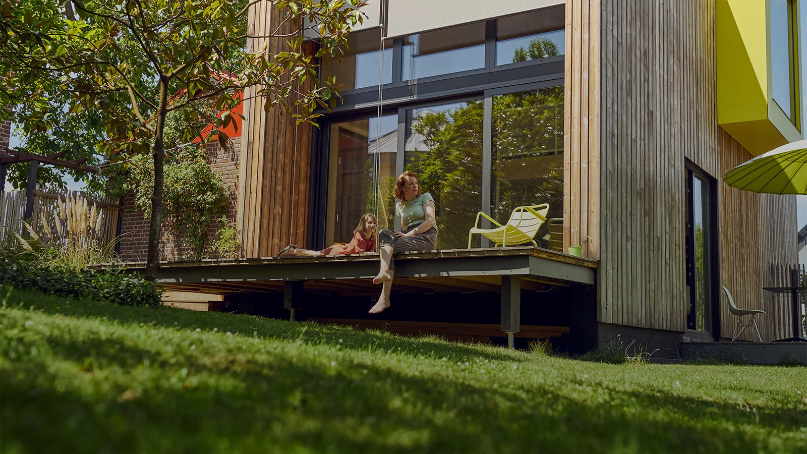 Bild einer Frau mit einem Kind, sitzend auf der Terrasse von einem Tiny House