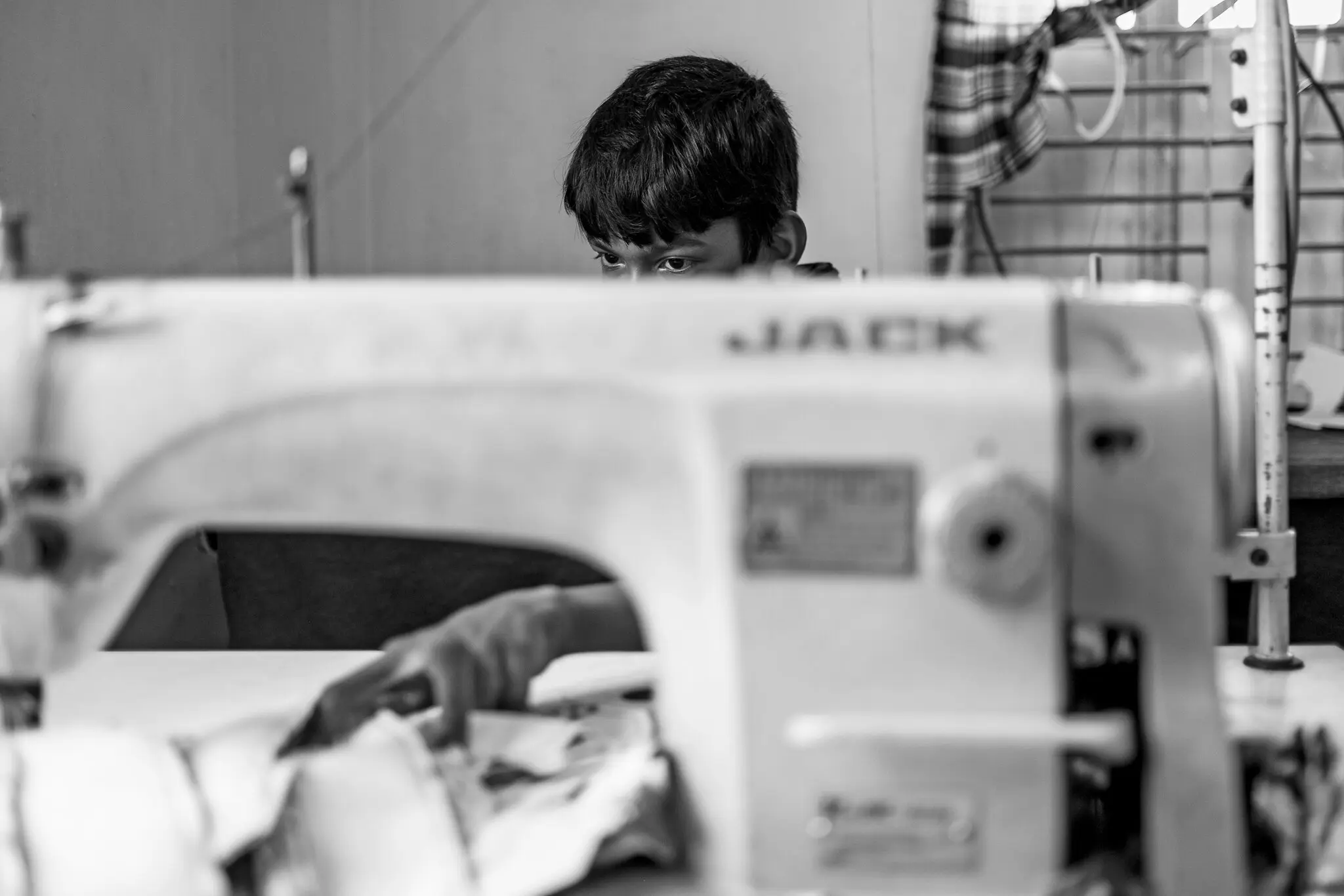 Young boy behind sewing machine.