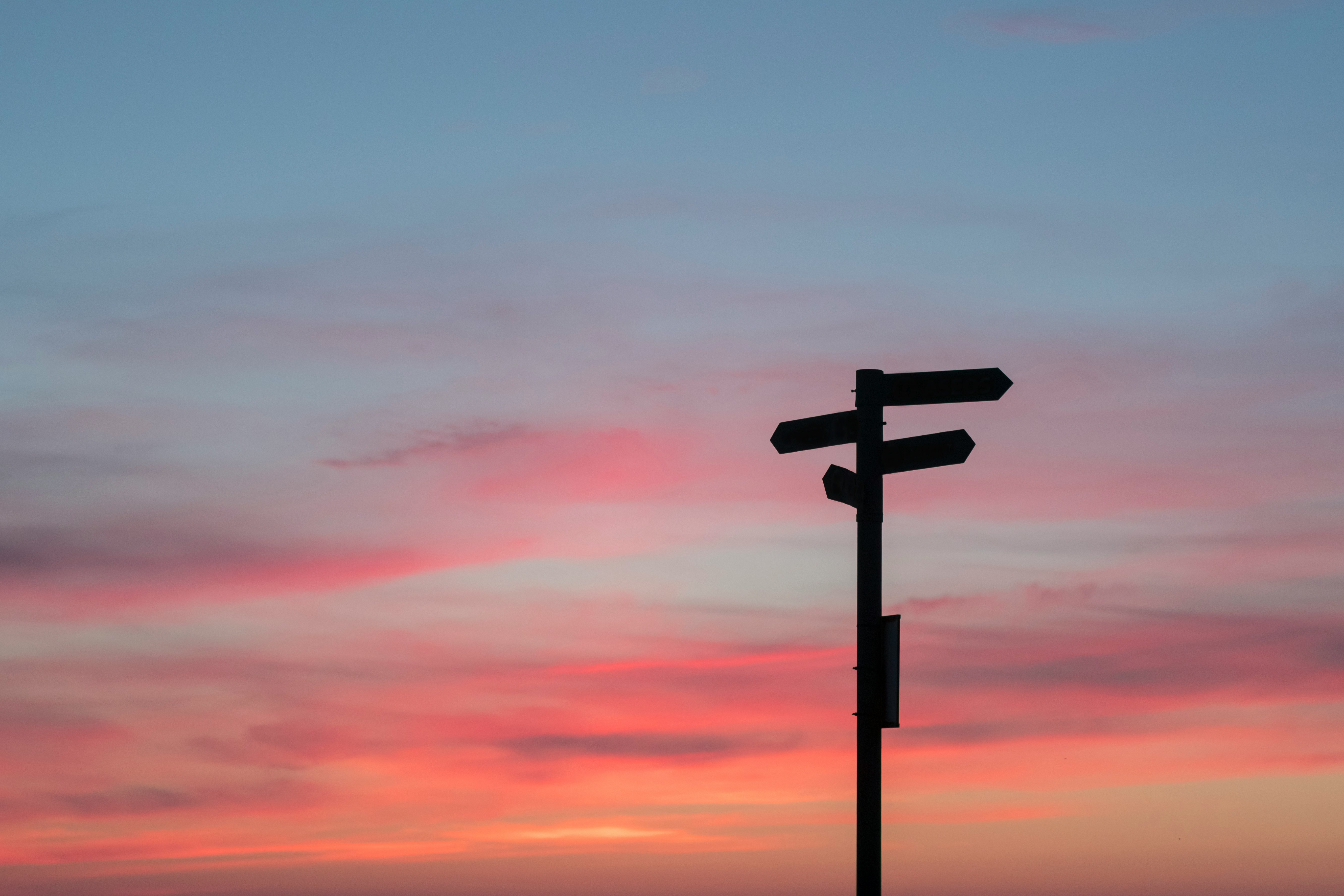 Silhouette of road signage against a golden sunset sky
