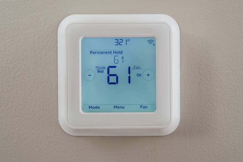 Programmable digital thermostat set to 61°F