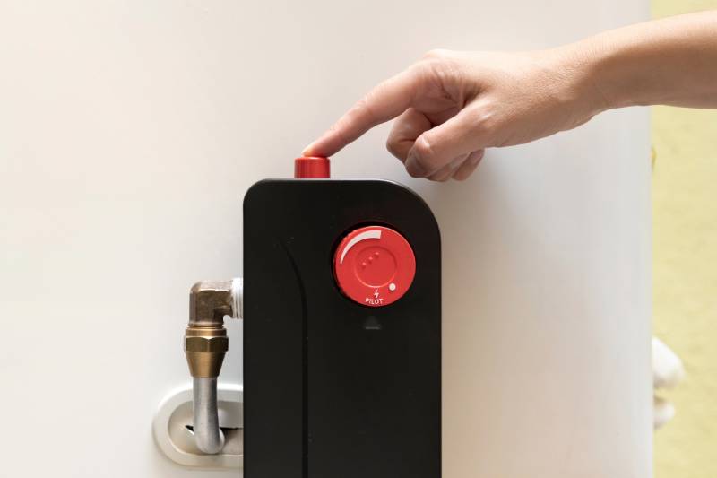 Finger pressing water heater reset button.
